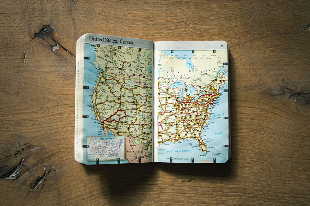 An atlas lies open to a map of the United States (Unsplash/Domino)