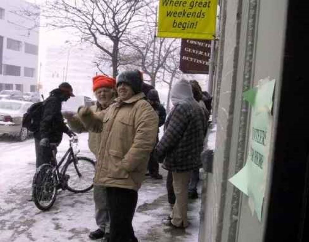 People, one with a bike, stand outside a building.