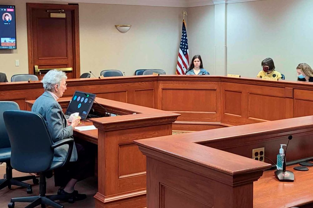 Woman sits in a courtroom, testifying.