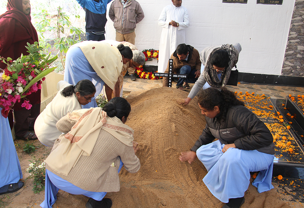 Sisters arrange flowers and level mud with their hands in Odisha (in the east of India), at the tomb of one of the sisters. (Tessy Jacob)