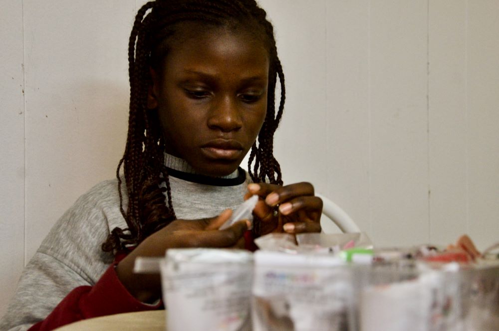 Aminata makes tiny ornaments for a construction paper Christmas tree Dec. 13, 2023, in the apartment she and her sister share in Chicago. (GSR photo/Dan Stockman)