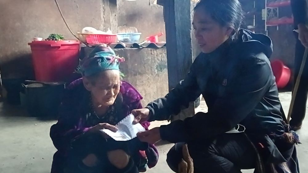 Lovers of the Holy Cross of Hung Hoa Sr. Mary Hoang Thi Phuong offers money as a Christmas gift to 90-year-old Maria Giang Thi Xay, whose house was a chapel for Hmong Catholics from Ban Phung Subparish in Lao Cai province. Her husband, who had evangelized local people, died in November. (Joachim Pham)