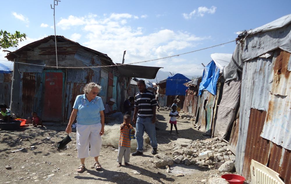 Woman walks with child in Haiti community