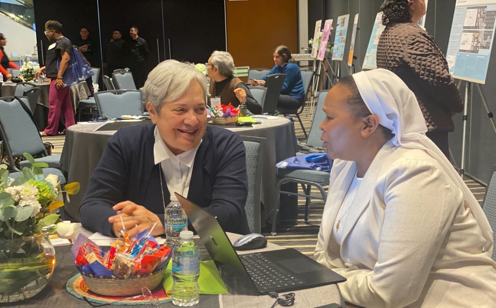 Two women sit at a table and talk.