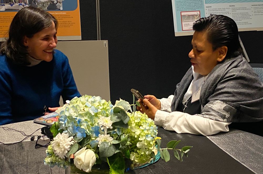 Two women sit at a table and talk.