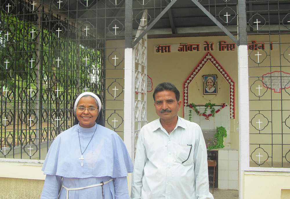 Sr. Selmy Paul and Samandar Singh pose in 2015 in front of what was Clarist Sr. Rani Maria Vattalil's tomb before her remains were exhumed and transferred to the interior of Sacred Heart Church in Udainagar, India. Singh, who stabbed Sister Rani Maria to death in 1995, attended her November beatification. (CNS/GSR/Saji Thomas)