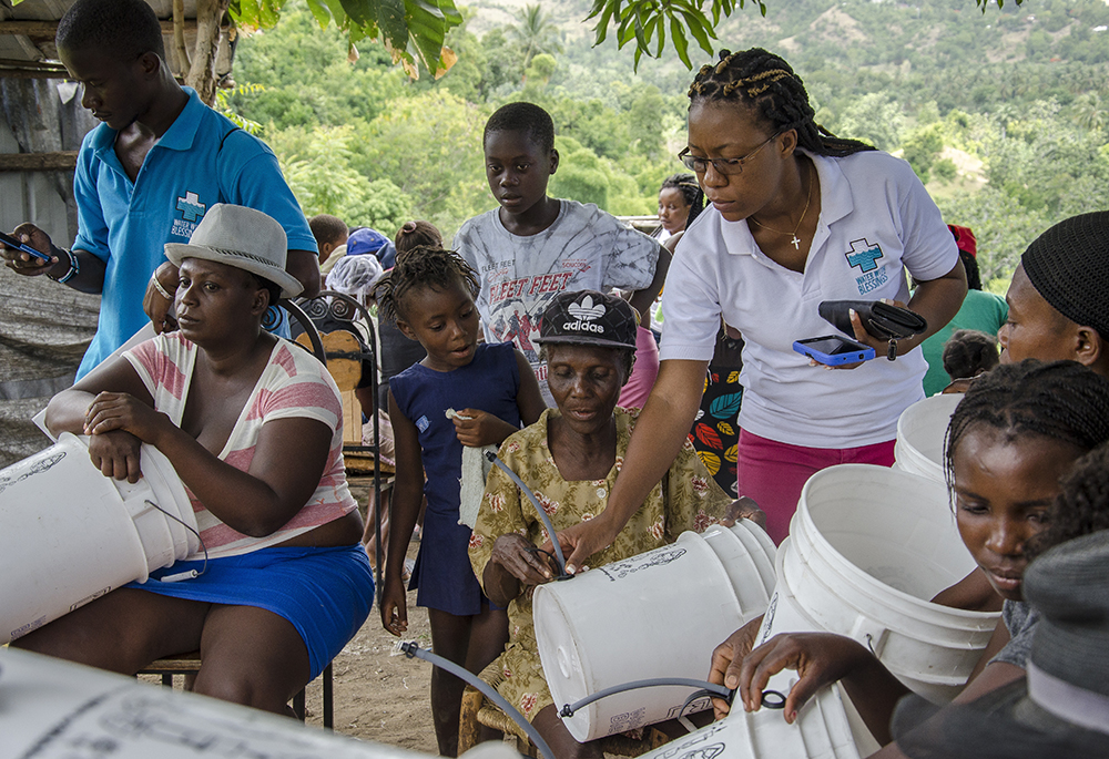 A Water With Blessings teacher in Anse-a-Veau, Haiti, collects GIS data and checks on hardware installation at the end of a 2018 training. (CNS/Courtesy of Water With Blessings/Corey Ohlenkamp)