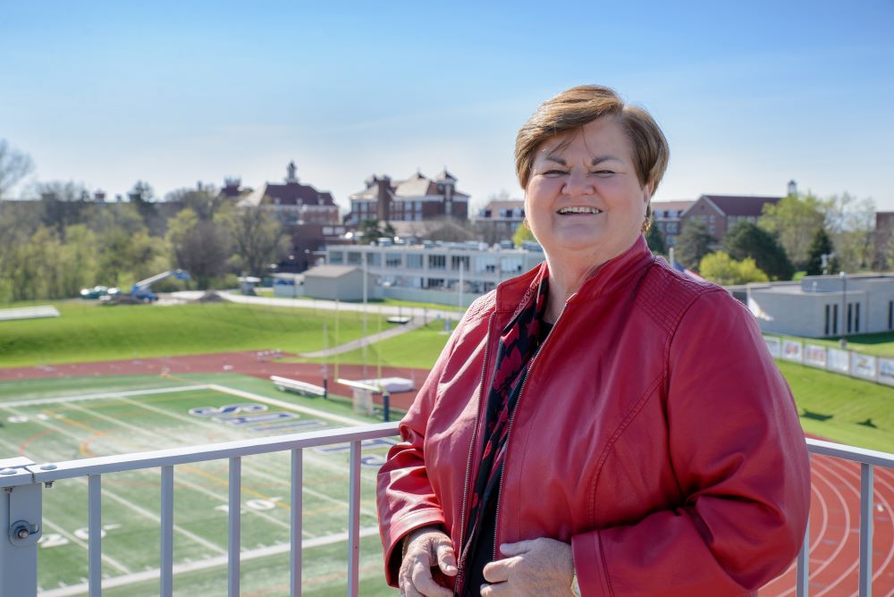 Sr. Peg Albert stands in box at college stadium.