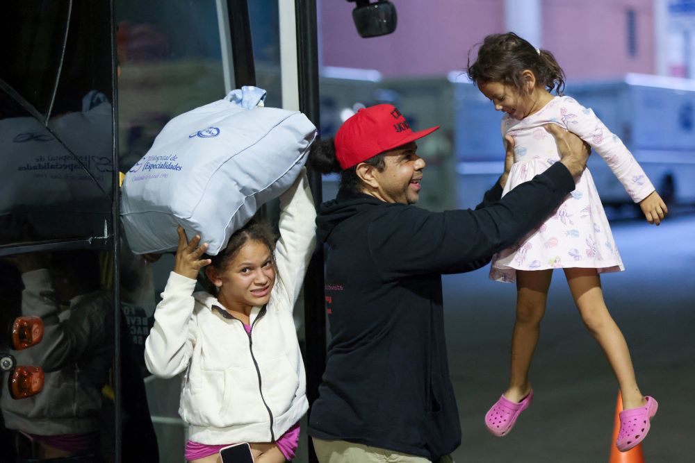 An aid worker greets migrants arriving from Texas by bus at the Port Authority bus terminal in New York City May 10. (OSV News/Reuters/Andrew Kelly)