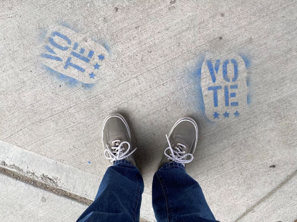 illustration of a person's feet on a sidewalk, with words "vote"