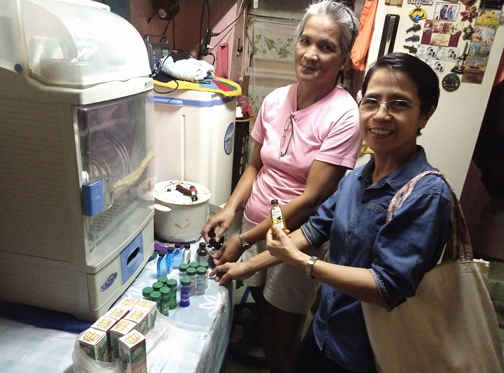 Francia, left, and Sister Arabella look at bottles of pain relievers, part of Francia's income-generating project on Sept. 2, 2023. Francia's house in Paco, Manila, Philippines, accommodates only two people. (Jerahmeel Cruz)