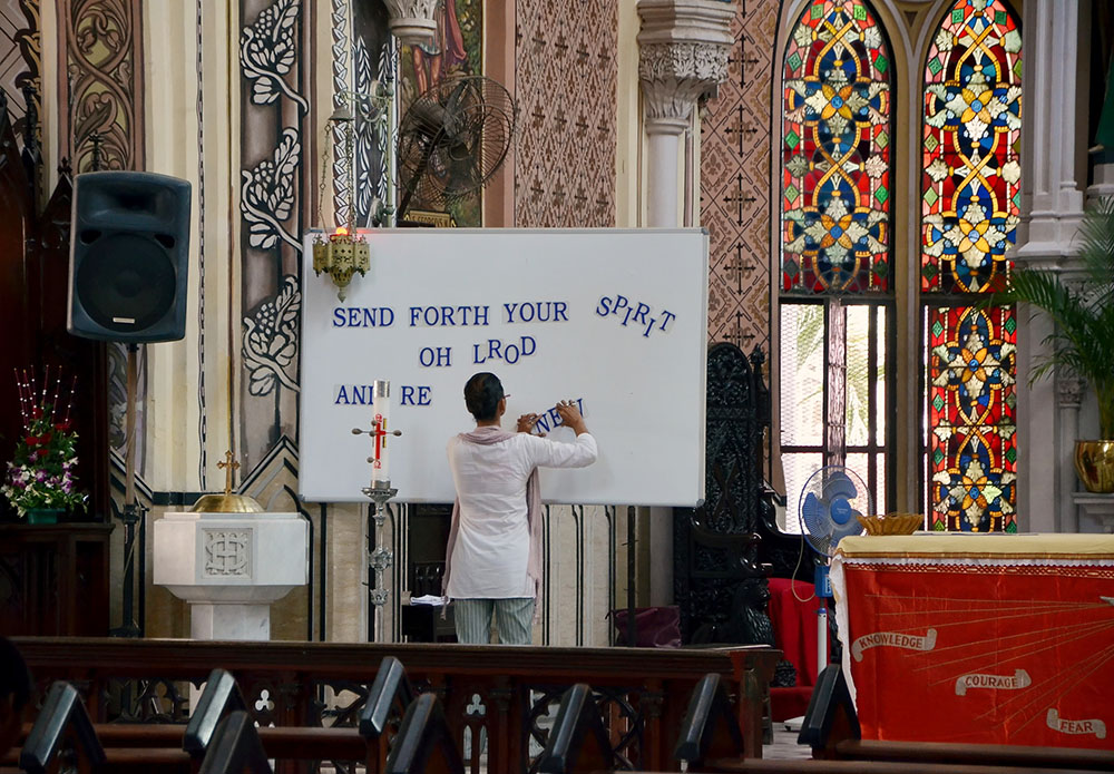 A young woman arranges a sign in the Catholic cathedral of Mumbai, India. (Dreamstime/Svglass)