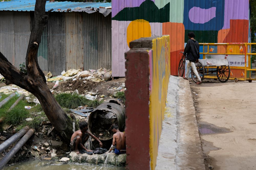 Laborers wash their clothes in sewage water under a bridge in New Delhi, India, on Aug. 24.