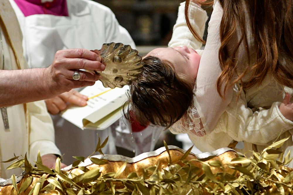 Pope Francis baptizes one of 13 babies during a Mass celebrating the feast of the Baptism of the Lord in the Sistine Chapel at the Vatican Jan. 8, 2023. 