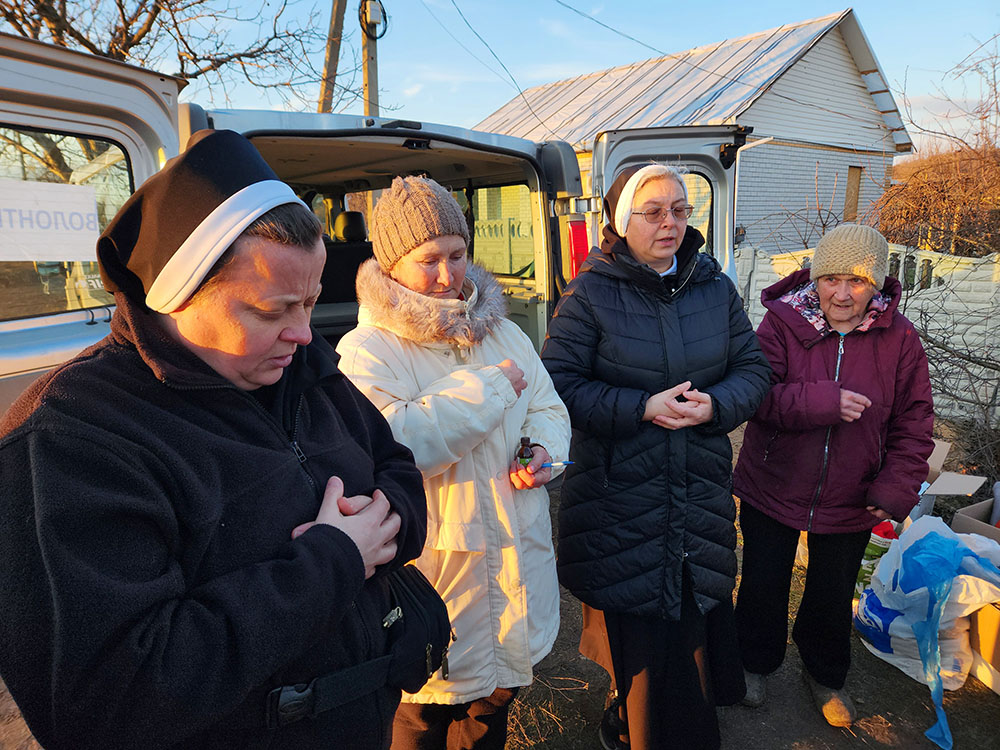 La Hna. Lucia Murashko dirige la oración de los habitantes del pueblo de Orihiv, en el este de Ucrania, tras una entrega de ayuda humanitaria. (Foto: GSR/Chris Herlinger)