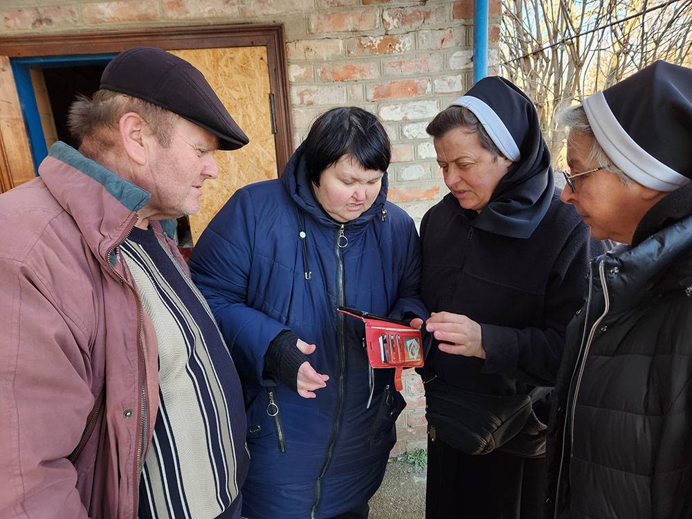 Inna Sirinok, and her husband, Yurii, left, with visiting Srs. Lucia Murashko and Romana Hutnyk, at the couple's destroyed home in the eastern Ukrainian village of Preobrazhenka (GSR photo/Chris Herlinger)