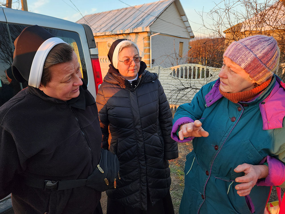 Srs. Lucia Murashko, left, and Romana Hutnyk, members of the Order of St. Basil the Great, speak to a resident of the village of Orihiv, in eastern Ukraine, during a delivery of humanitarian supplies earlier this month. (GSR photo/Chris Herlinger)