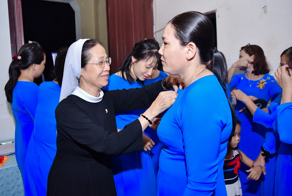 Daughters of Our Lady of the Visitation Sr. Do Thi Thien dresses a woman in ao dai, or Vietnamese traditional dress, to celebrate the Tet festival. Thien said the nuns make tens of sets of ao dai to give to lay volunteers who cooperate with them by providing basic education for children and caring for patients. (Joachim Pham)