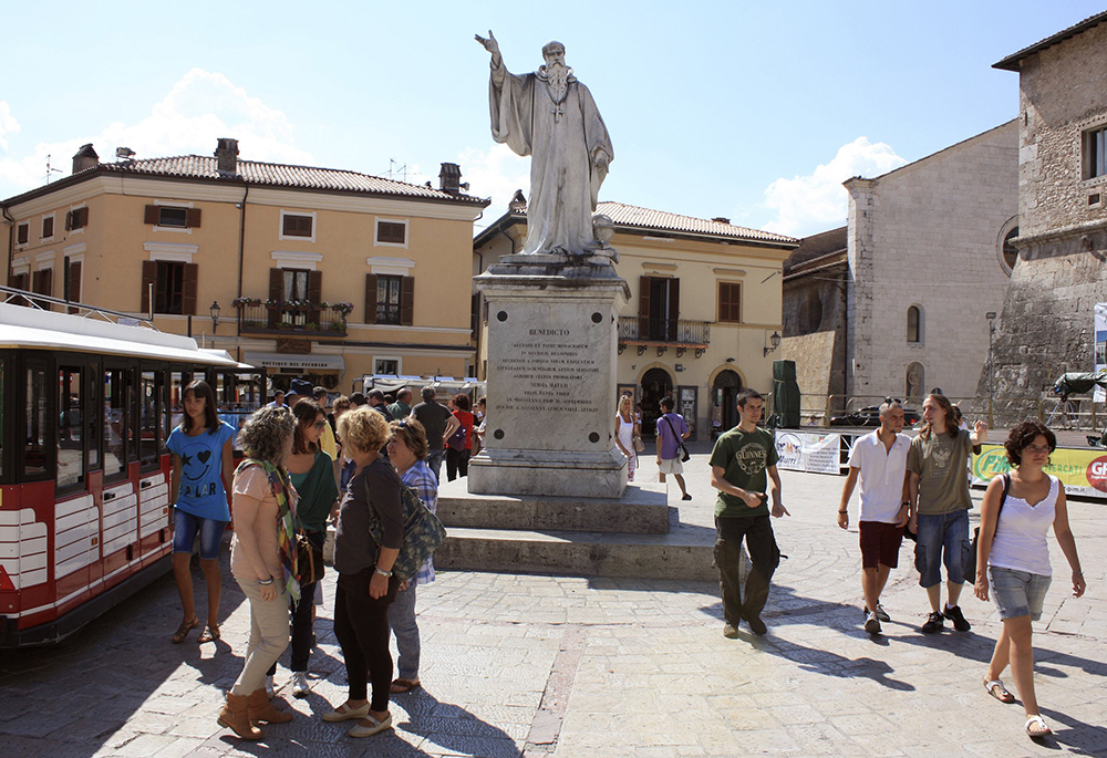Tourists and townspeople surround a statue of St. Benedict Aug. 14, 2013, in the small Italian town of Norcia. (CNS/Henry Daggett)