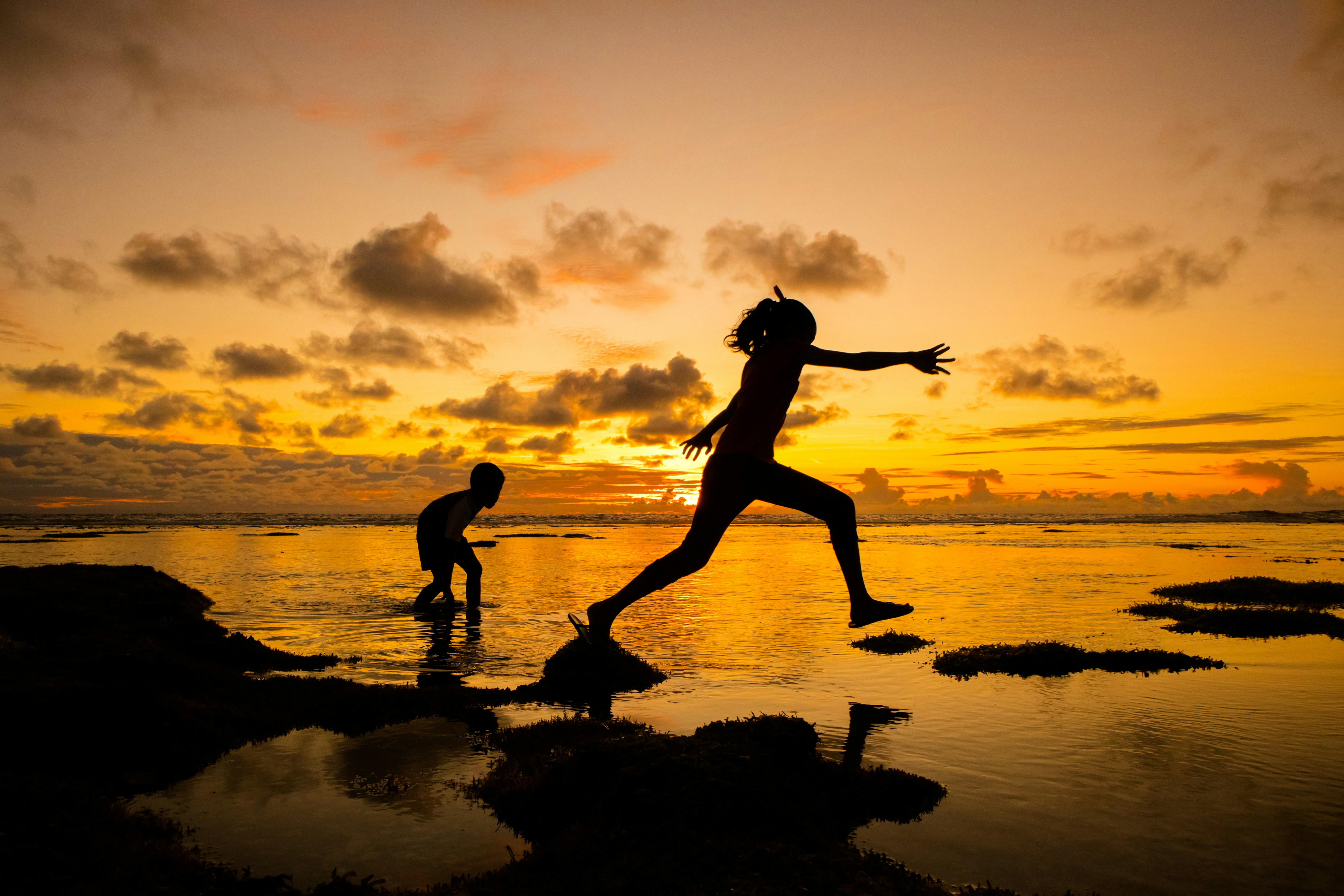 Two people, one chasing the other, amid sunset