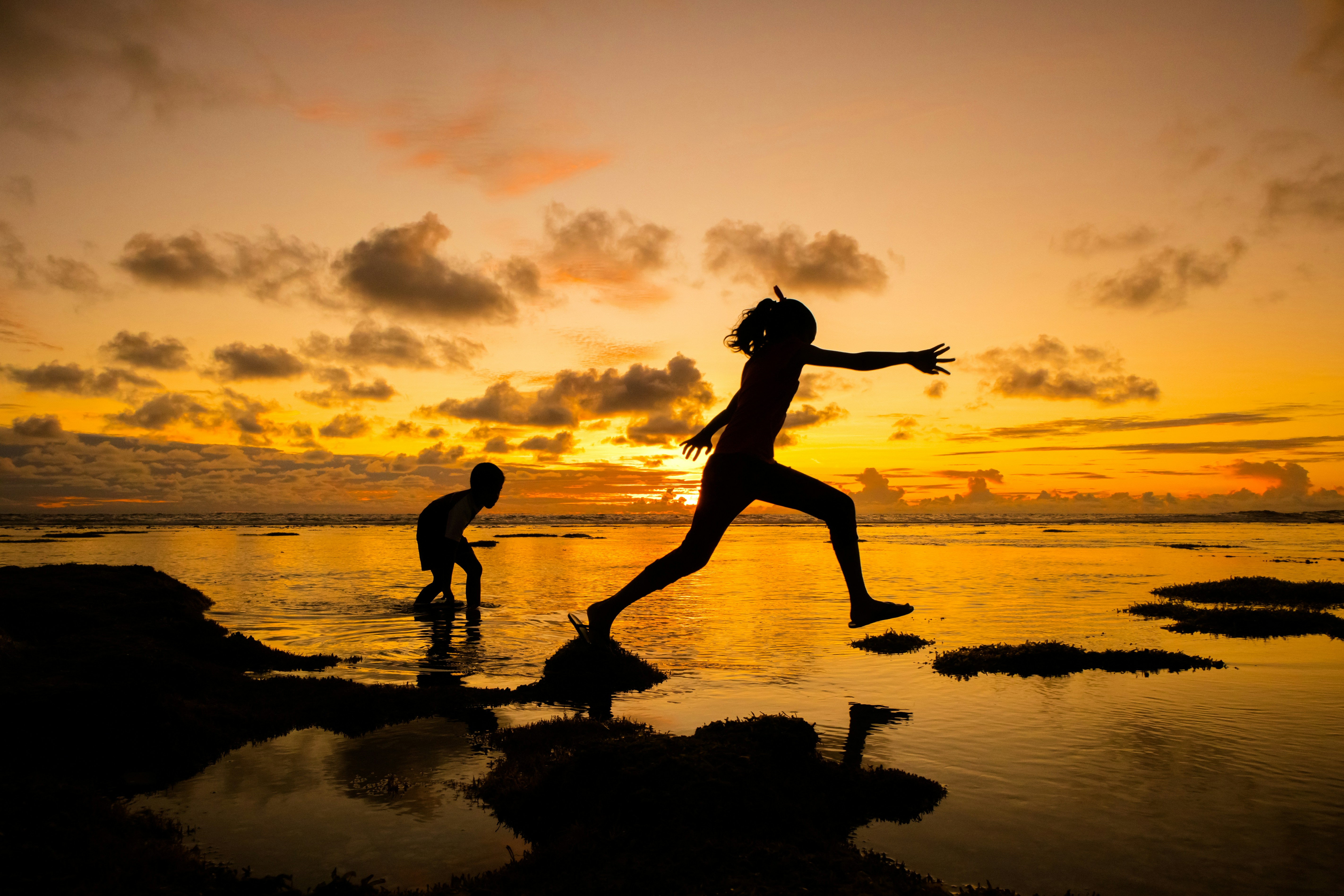 Two people, one chasing the other, amid sunset 