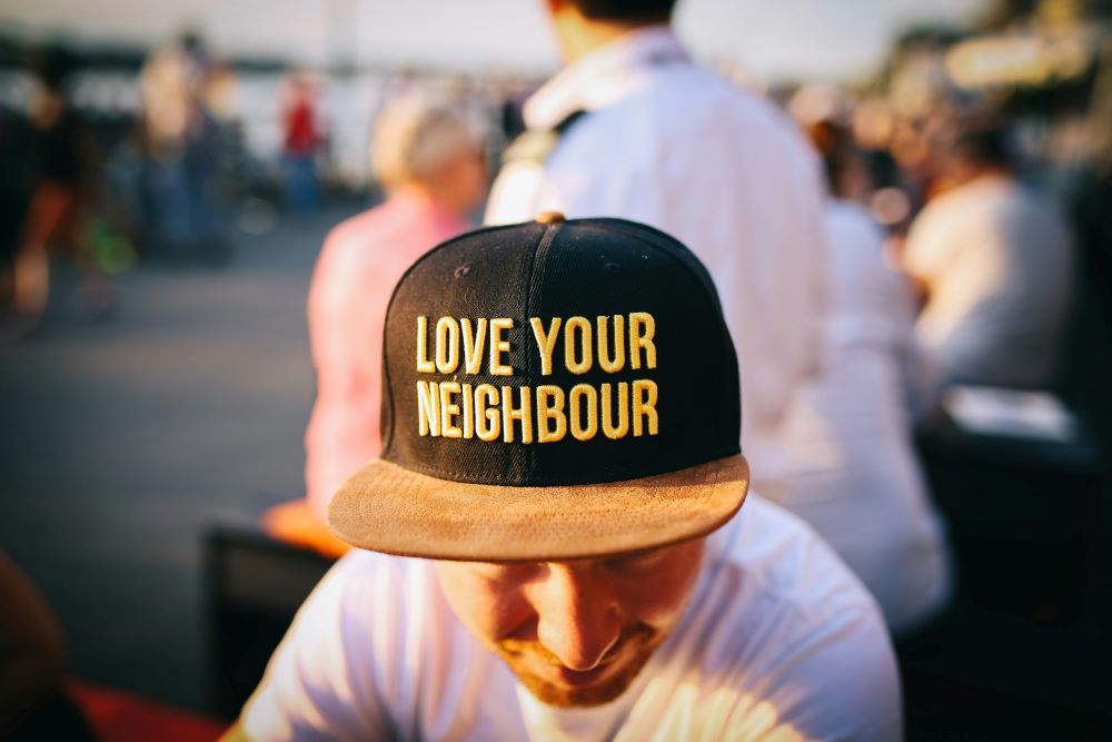 front of baseball cap reads "Love your neighbor."