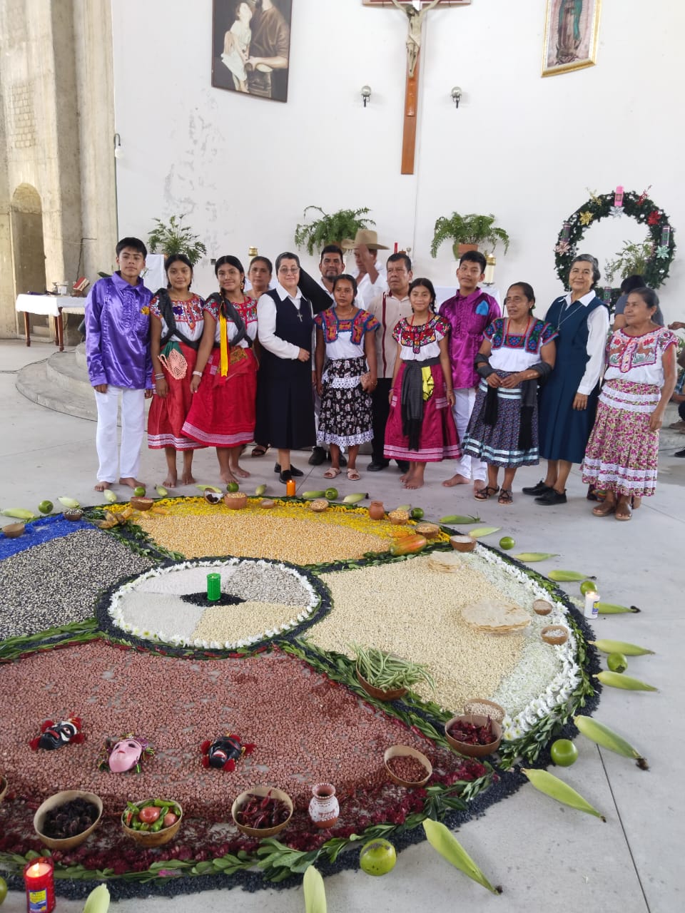 La Hna. Alicia Guevara Pérez, la segunda desde la derecha, junto a un grupo de indígenas de la cultura mixteca, durante la celebración de san Juan Diego, patrono de las comunidades indígenas, en la Catedral de Puerto Escondido, Oaxaca, el 9 de diciembre de 2023. En el suelo se puede observar el 'altar cósmico' que se realiza con diferentes semillas y representa la vida y el trabajo de los indígenas. (Foto: cortesía Hna. Alicia Guevara P.)