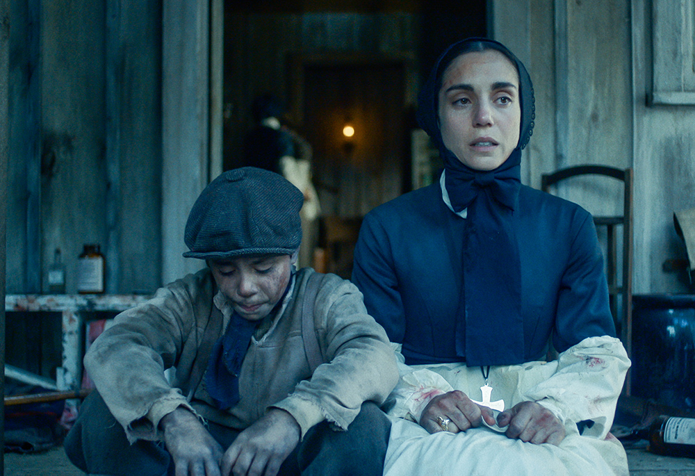 In a still from the new film "Cabrini," Mother Cabrini, played by Italian actress Cristiana Dell'Anna, is seen in a scene early in the film, sitting next to one of her orphans during her initial ministry on the streets of New York. (Courtesy of Angel Studios)