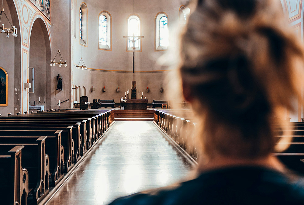 Woman enters an empty church (Unsplash/Thomas Vitali)