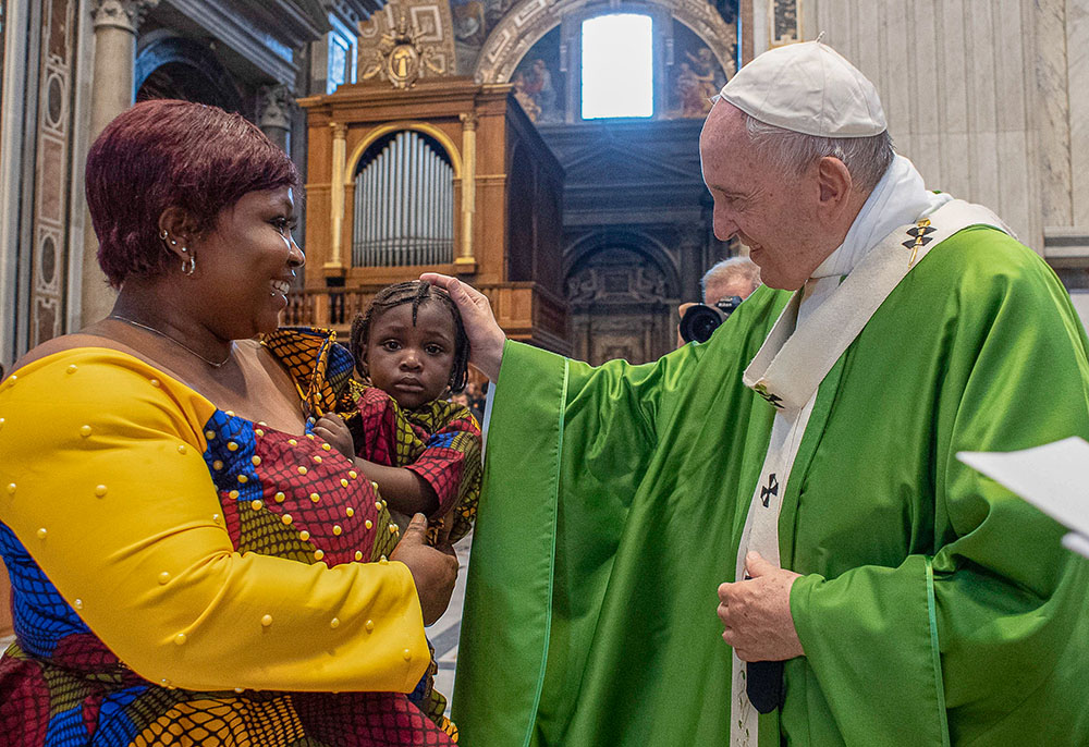 Pope Francis greets a woman and child during a July 8, 2019, Mass in St. Peter's Basilica at the Vatican commemorating the sixth anniversary of his visit to the southern Mediterranean island of Lampedusa. (CNS/Vatican Media)