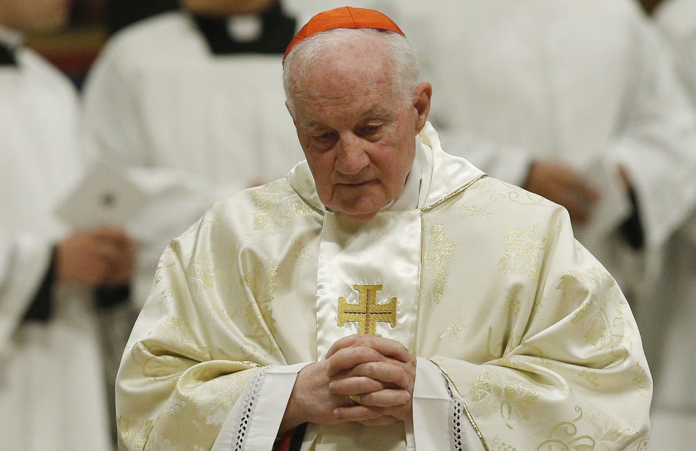 Cardinal Marc Ouellet. Prelate, vested, bows head and folds hands in prayer.