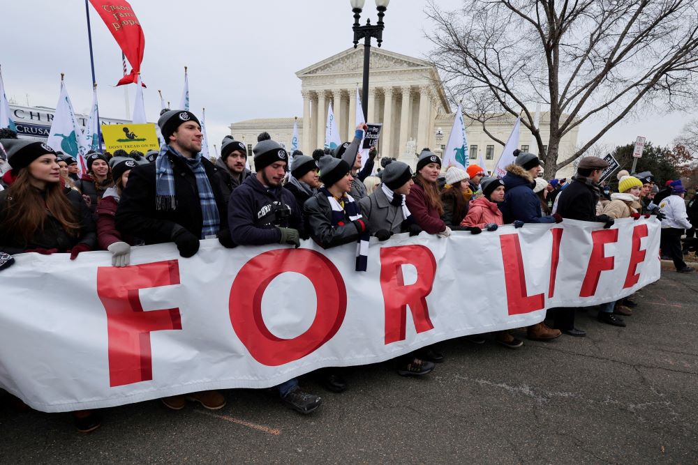 People carry a banner past the U.S. Supreme Court while participating in the 49th annual March for Life in Washington Jan. 21, 2022. 