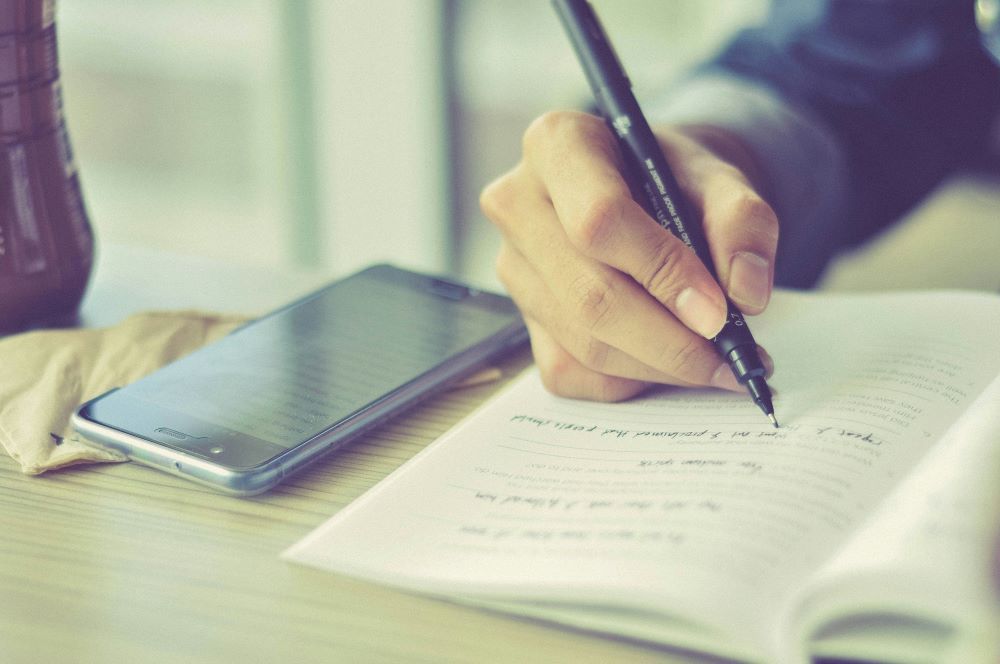 Persona escribe en un cuaderno. 