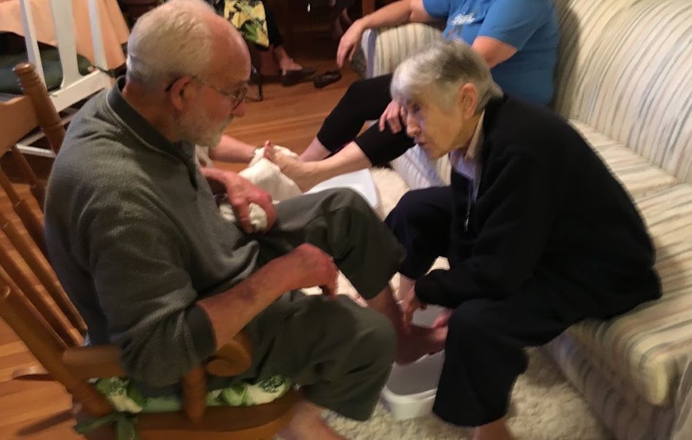 Sister of Charity Marie de Paul Combo washes the feet of Christian Br. Louis Rodemann, longtime leader at Kansas City's Holy Family Catholic Worker House, during a Holy Thursday Seder service. Combo died April 1 at age 99. (Courtesy of Thomas C. Fox) 