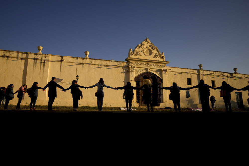 Women join hands to form a chain outside convent