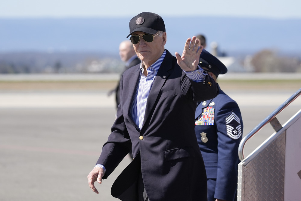 President Biden waves as he departs presidential plane. 