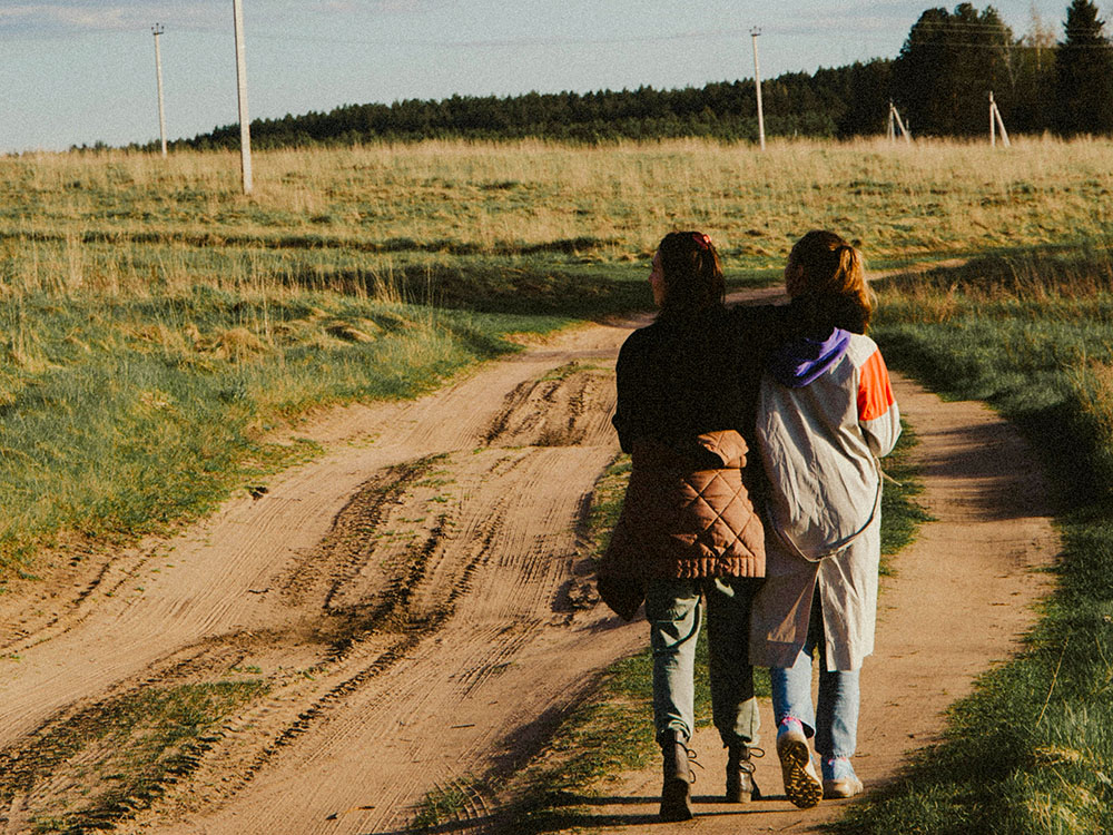 Two friends walking along a dirt road (Unsplash/Klara Kulikova)