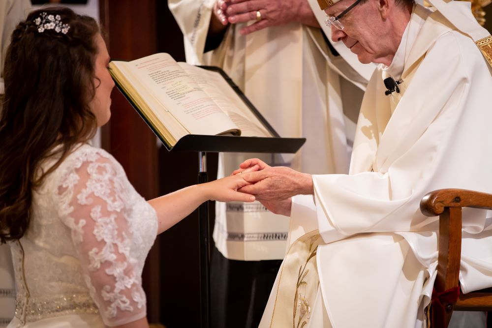 Claire Halbur, one of the cast members of Lifetime's "The Sisterhood," receives the bridal ring from Bishop Thomas Olmsted during the Rite of Consecration of a Virgin Living in the World on Aug. 22, 2020. 