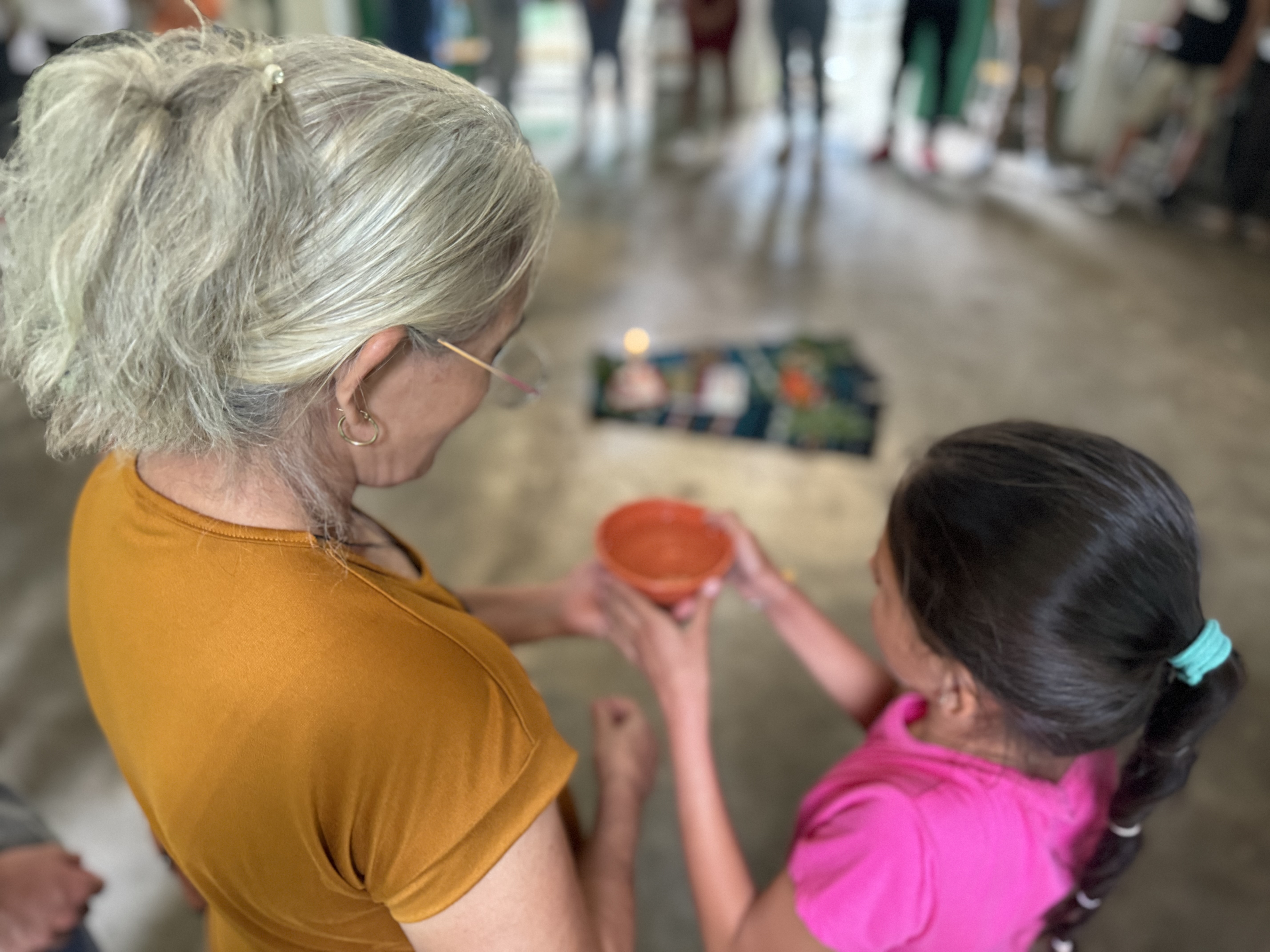 Una sobreviviente de una masacre comparte agua del río Sumpul con una niña; ambas participaron en una actividad intergeneracional, el 27 de abril 2024 en Arcatao, El Salvador, para recordar la emboscada y masacre del ejército salvadoreño contra más de 600 personas el 14 mayo de 1980.  (Foto: Rhina Guidos/GSR) 