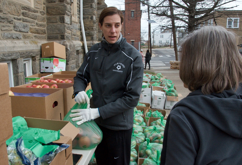Sr. Liz McGill, a novice with the Sisters of St. Joseph of Philadelphia, unpacks apples to hand out during the SSJ Neighborhood Center's monthly food distribution day, March 20 in Camden, New Jersey. (GSR photo/Dan Stockman)