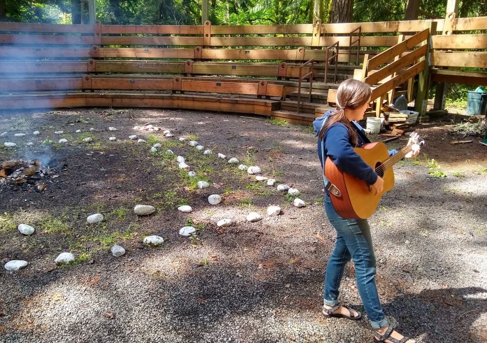 Sr. Terri Schell plays guitar around a campfire. Sr. Terri Schell plays guitar around a campfire.