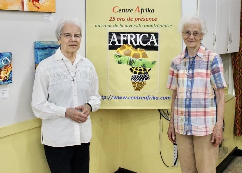 Hermanas Monique Bonnefoy, a la izquierda, y Rita Toutant, de las Hermanas Misioneras de Nuestra Señora de África Las hermanas Monique Bonnefoy, a la izquierda, y Rita Toutant, de las Hermanas Misioneras de Nuestra Señora de África, junto a un cartel que en francés reza: "25 años en el corazón de la diversidad de Montreal", en el Centre Afrika. Las dos trabajaron muchos años en África y ahora ejercen su ministerio en el centro intercultural de Montreal, Canadá. (Foto: GSR/Joanna Kozakiewicz)