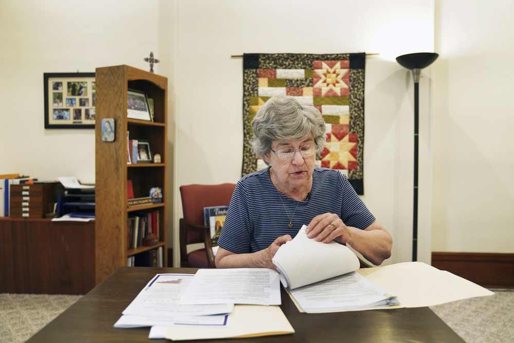 Benedictine Sr. Barbara McCracken, Mount St. Scholastica, Atchison, Kansas, July 16, 2024. Sr. McCracken sits at desk going through papers.