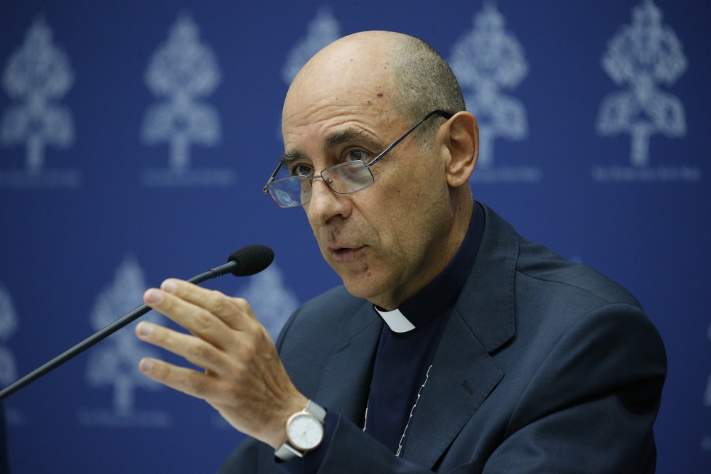 Cardinal Victor Manuel Fernandez, Medjugorje press conference, Sept. 19, 2024, Vatican City. Fernandez sits at panel desk in front of blue and white background, and speaks into microphone.