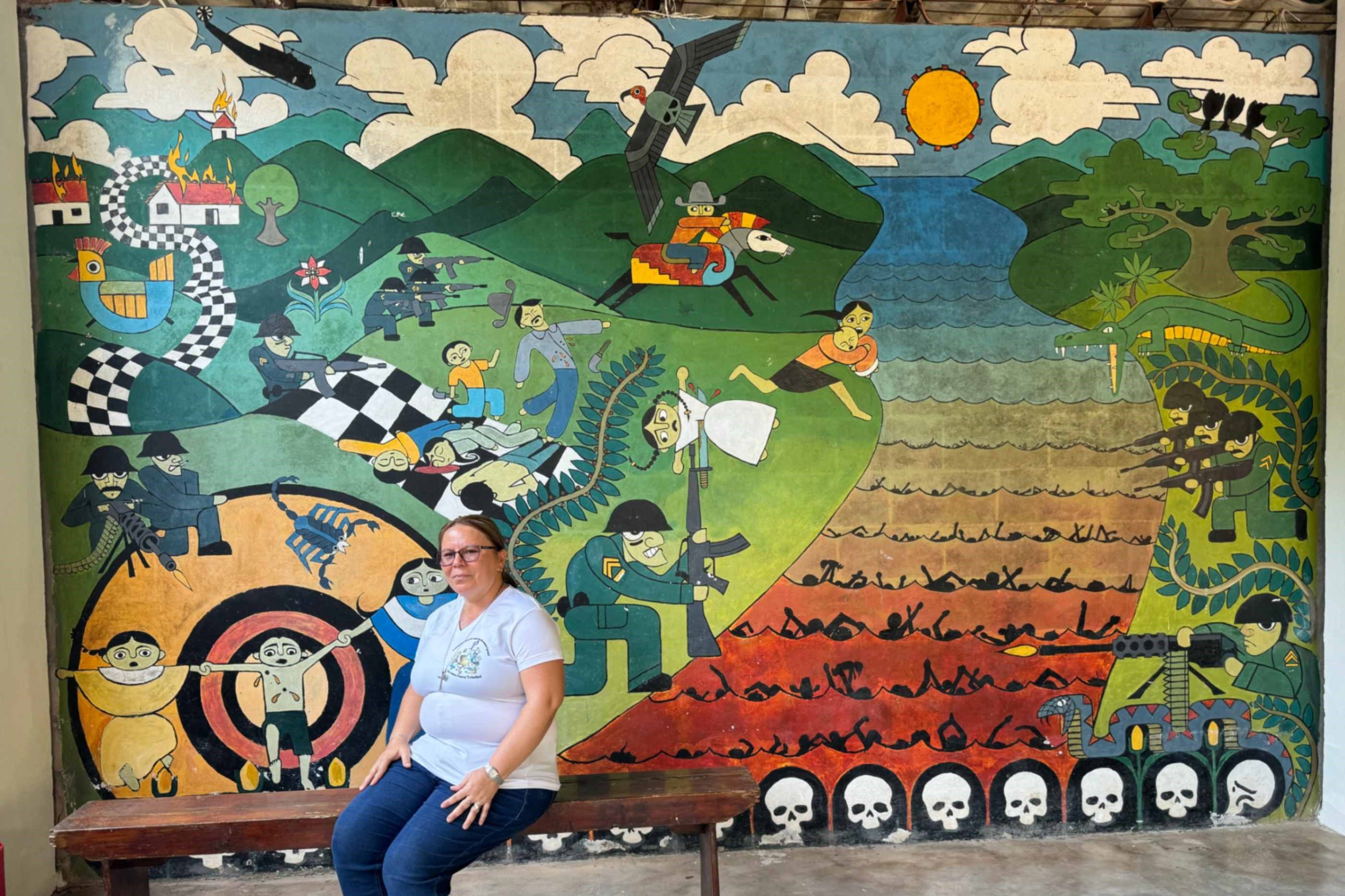 La hermana de la Providencia Vilma Franco se sienta en un banco en su ciudad natal de Arcatao, El Salvador, el 27 de abril de 2024, frente a un mural que representa la masacre de 1980 en el río Sumpul. Cada año, organizaciones como la Asociación Sumpul recuerdan la masacre de más de 600 personas por las fuerzas armadas salvadoreñas, un esfuerzo para educar y prevenir que tales actos se repitan. La hermana de la Providencia Vilma Franco se sienta en un banco en su ciudad natal de Arcatao, El Salvador, el 27 de abril de 2024, frente a un mural que representa la masacre de 1980 en el río Sumpul. Cada año, organizaciones como la Asociación Sumpul recuerdan la masacre de más de 600 personas por las fuerzas armadas salvadoreñas, un esfuerzo para educar y prevenir que tales actos se repitan. (Foto: Rhina Guidos/GSR)