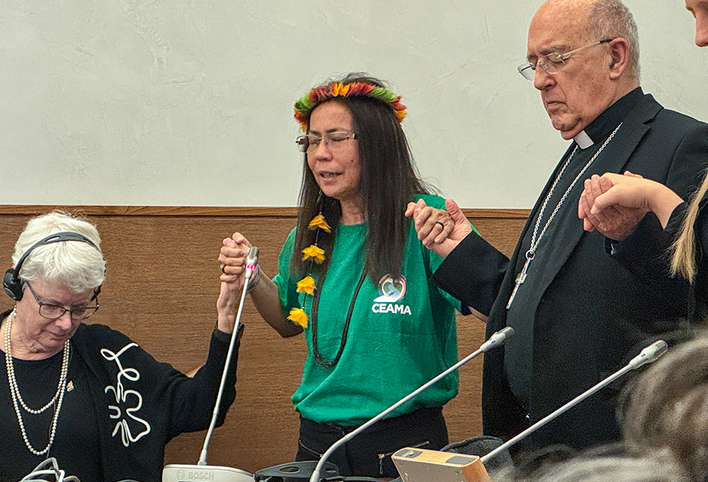 La catequista franciscana Hna. Laura Vicuña Pereira Manso, de la Conferencia Eclesial del Amazonas, en el centro de verde, dirige una oración el 4 de octubre de 2024 después de un panel sobre la sinodalidad y el ministerio de las mujeres en el Aula Papa Pío XI en Roma. La catequista franciscana Hna. Laura Vicuña Pereira Manso, de la Conferencia Eclesial del Amazonas, en el centro de verde, dirige una oración el 4 de octubre de 2024 después de un panel sobre la sinodalidad y el ministerio de las mujeres en el Aula Papa Pío XI en Roma. Manso dijo que ocuparse de tareas que normalmente realizaría un diácono forma parte de la vida diaria de algunas religiosas, ya que hay pocos agentes de pastoral en la remota región del Amazonas donde ella trabaja. (Foto: Rhina Guidos/GSR)