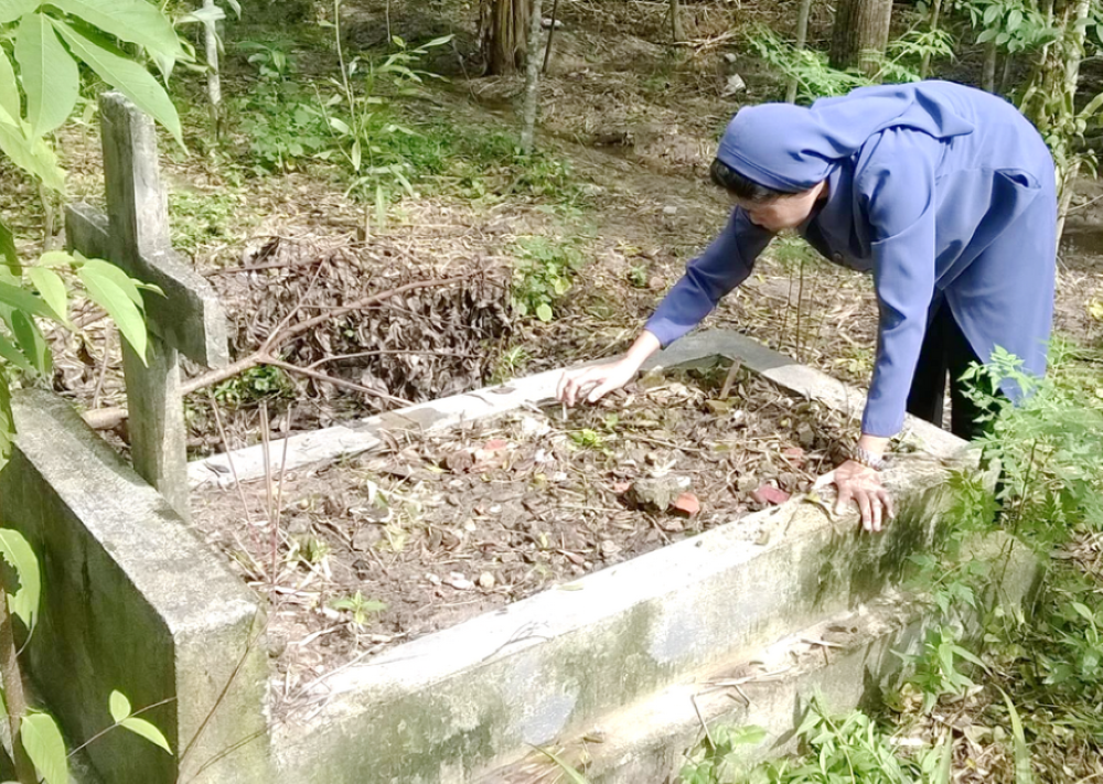 Sr. Martha Tran Thi Toan removes weeds from a neglected grave. Sr. Martha Tran Thi Toan removes weeds from a neglected grave.