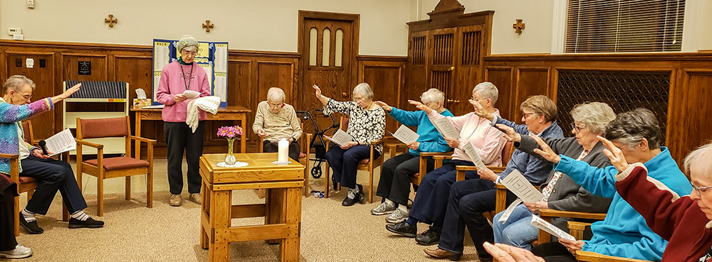 The Notre Dame Sisters of Omaha, Nebraska, pray for Sr. Theresa Maly (third from left) at her prayer shawl ceremony, held when a sister transitions to a care facility. She is presented with a shawl that symbolizes the community's love and prayers for her. (Courtesy of the Sisters of Notre Dame of Omaha)