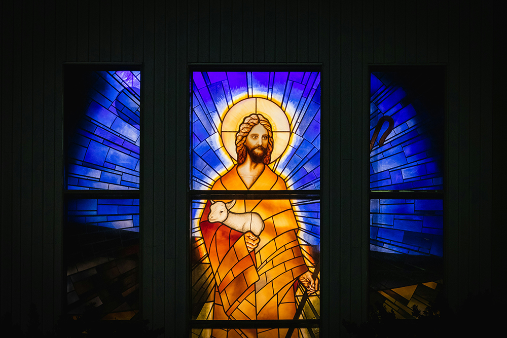 Jesus holding a lamb in stained glass (Unsplash/Greg Rosenke)
