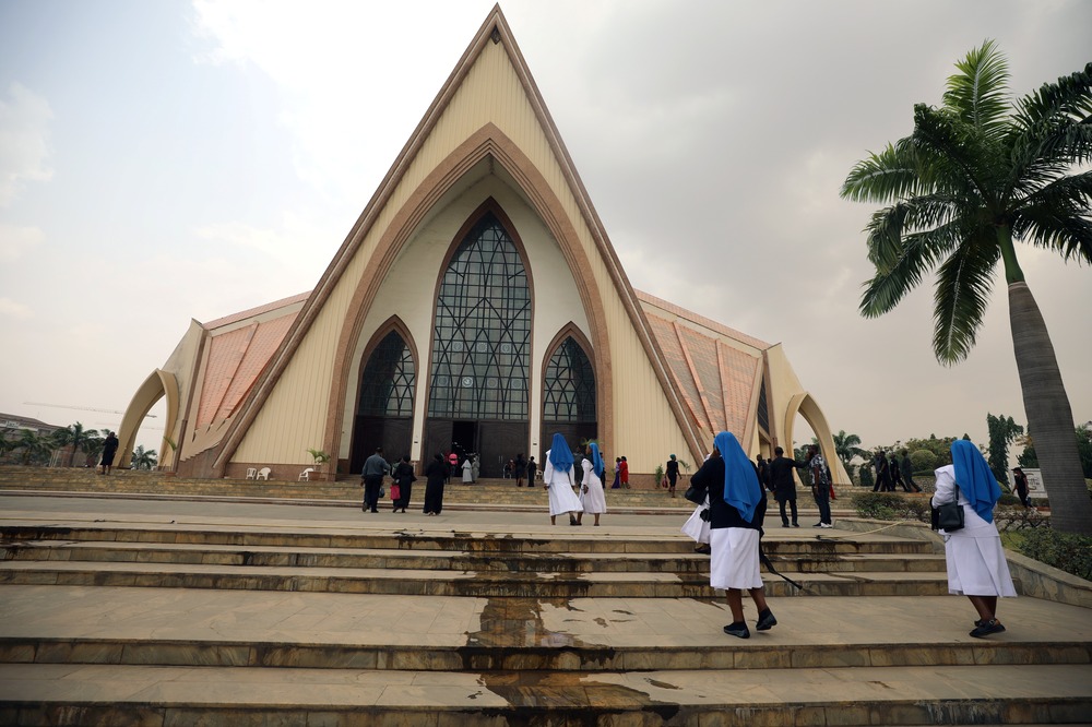 Nigerian women religious. Habited sisters walking up steps to church building.